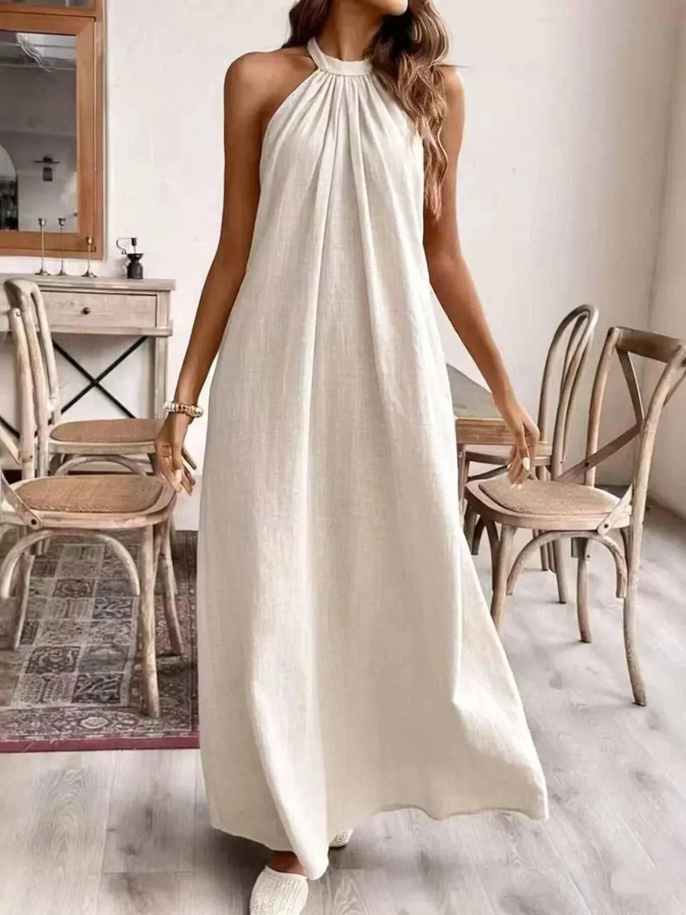 Woman wearing a ruched halter neck maxi dress made of slightly stretchy polyester fabric