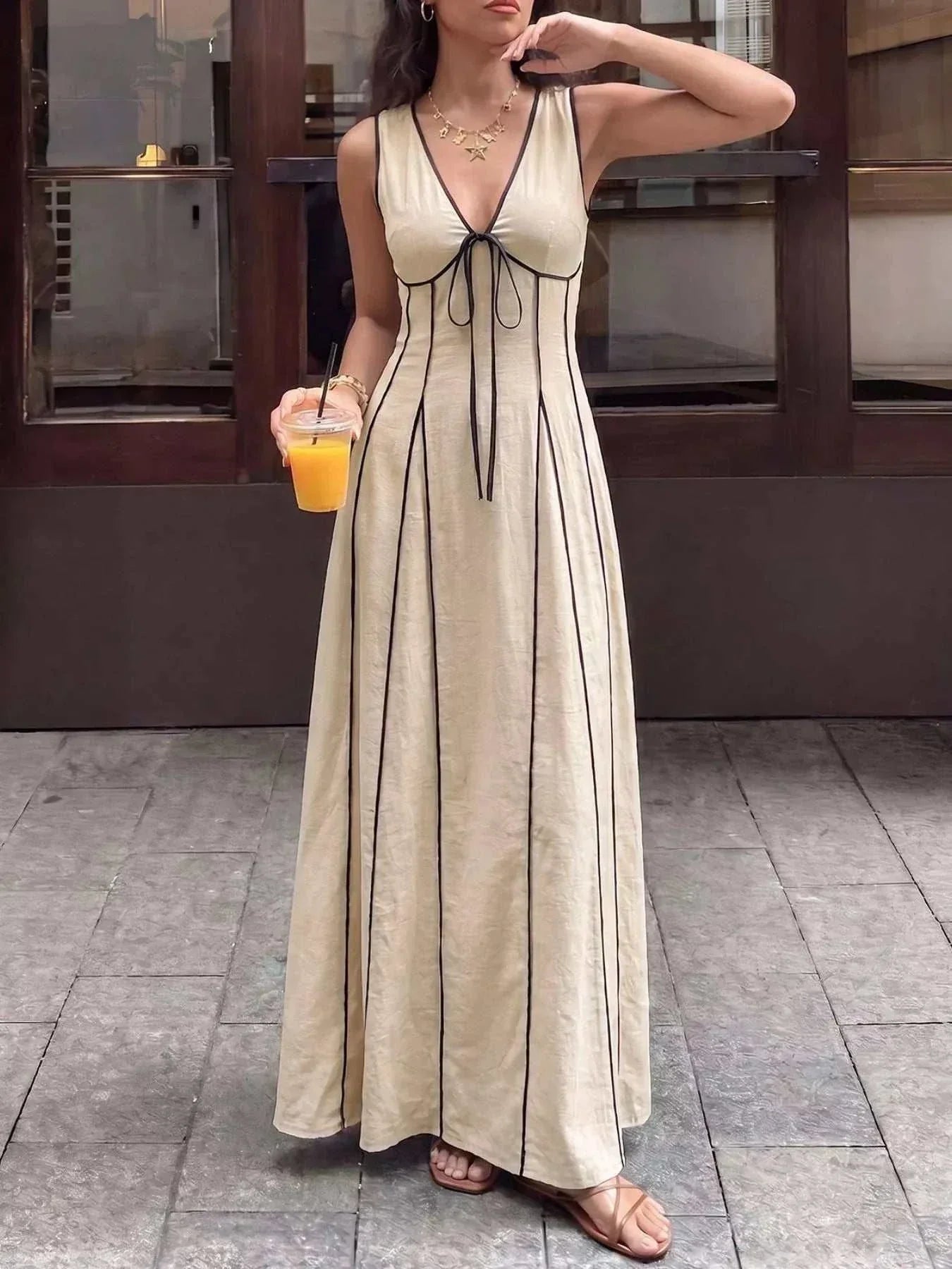 Woman wearing a V-neck sleeveless maxi dress with tie and zipper details