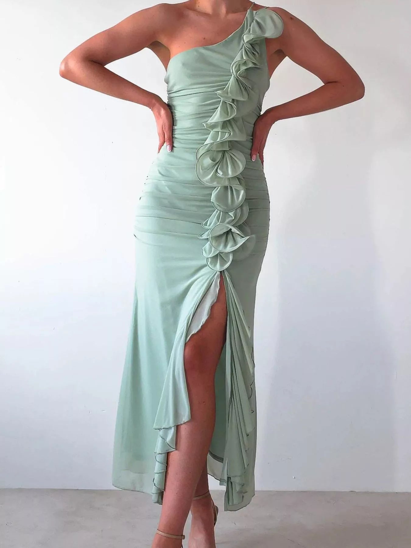 Model wearing a one-shoulder ruffle slit dress with ruched detail and zipper closure