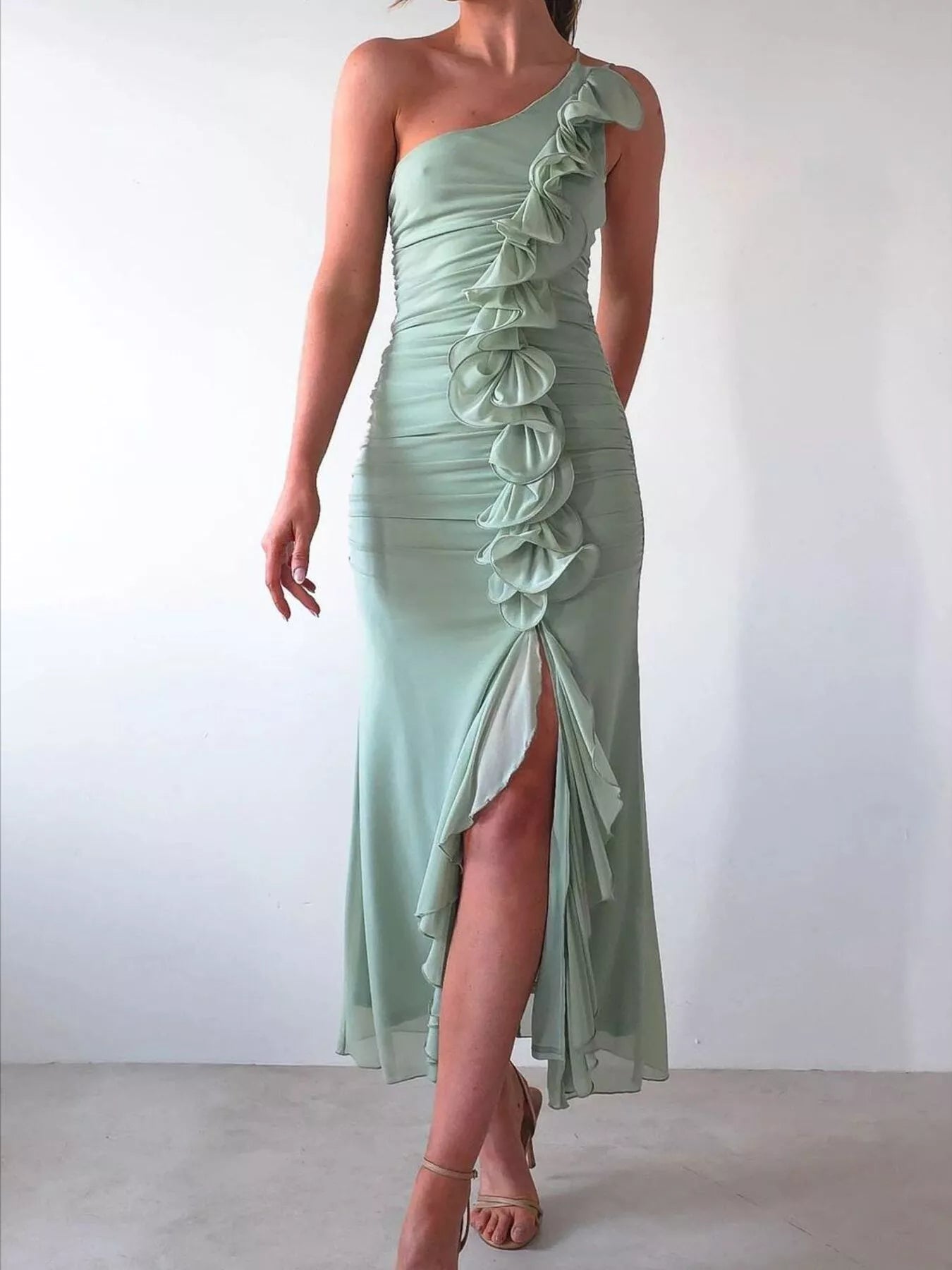 Woman wearing one-shoulder ruffle slit dress with ruched detail and zipper