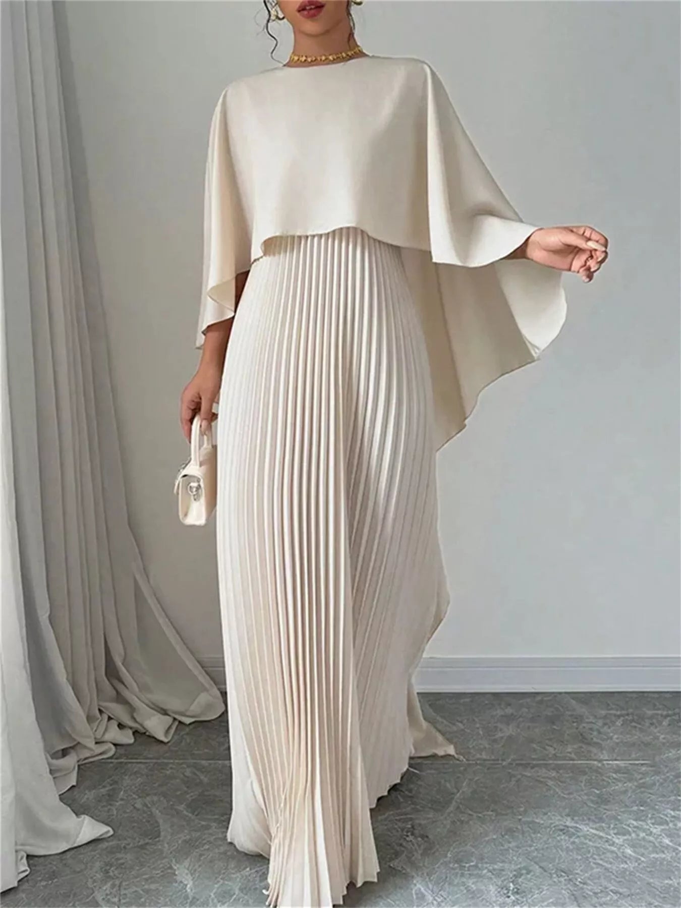 Woman wearing a black cape pleated maxi dress with no stretch and machine washable polyester fabric