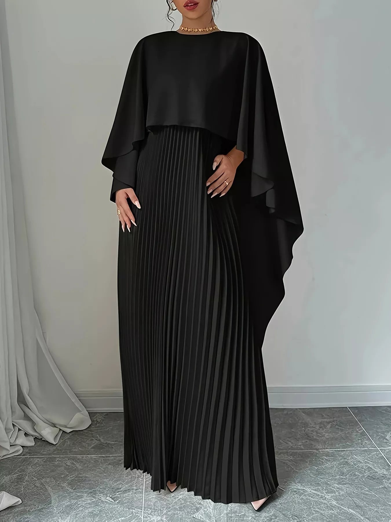Woman wearing a pleated cape maxi dress in polyester fabric
