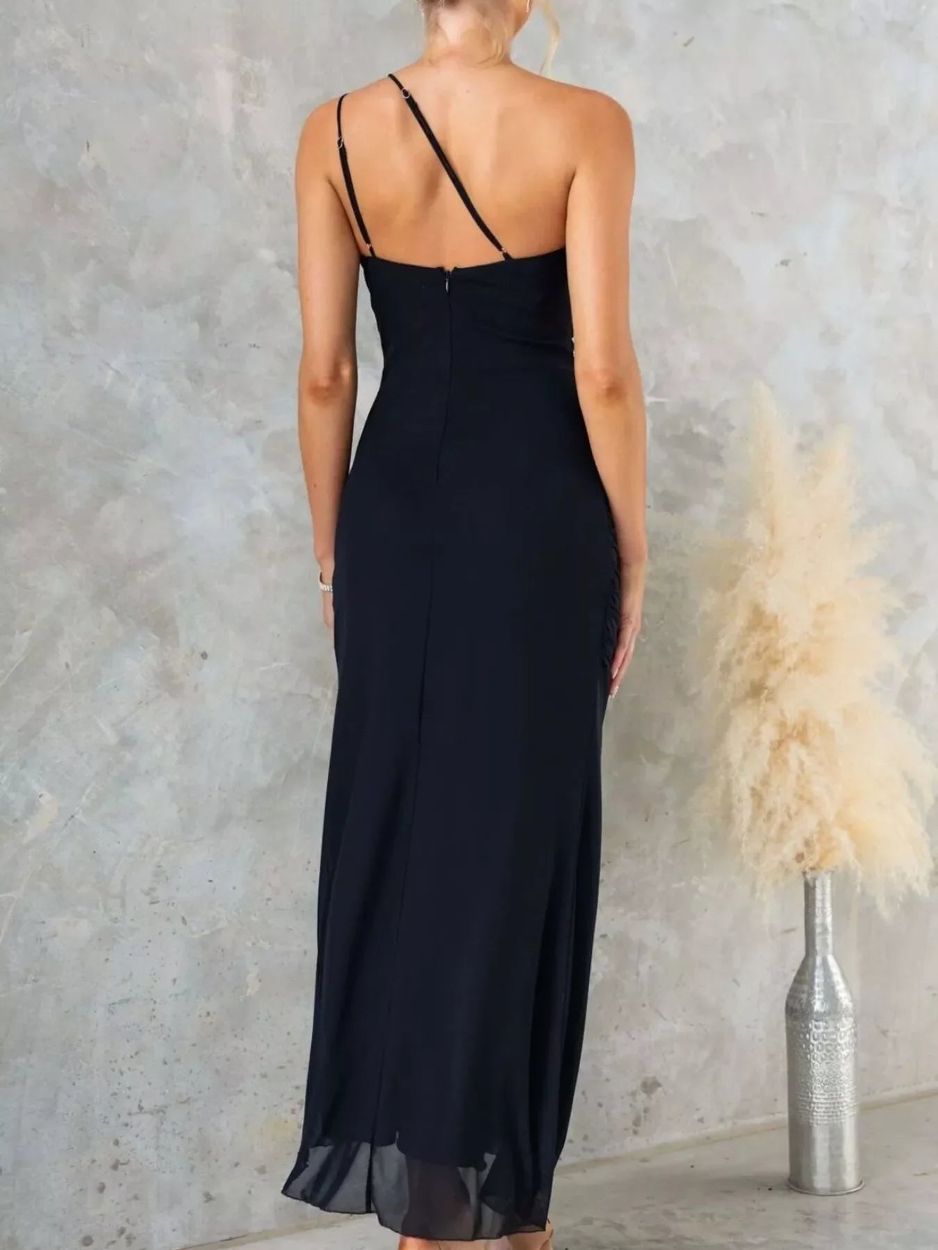 Model wearing a one-shoulder ruffle slit dress with ruched detailing and zipper closure
