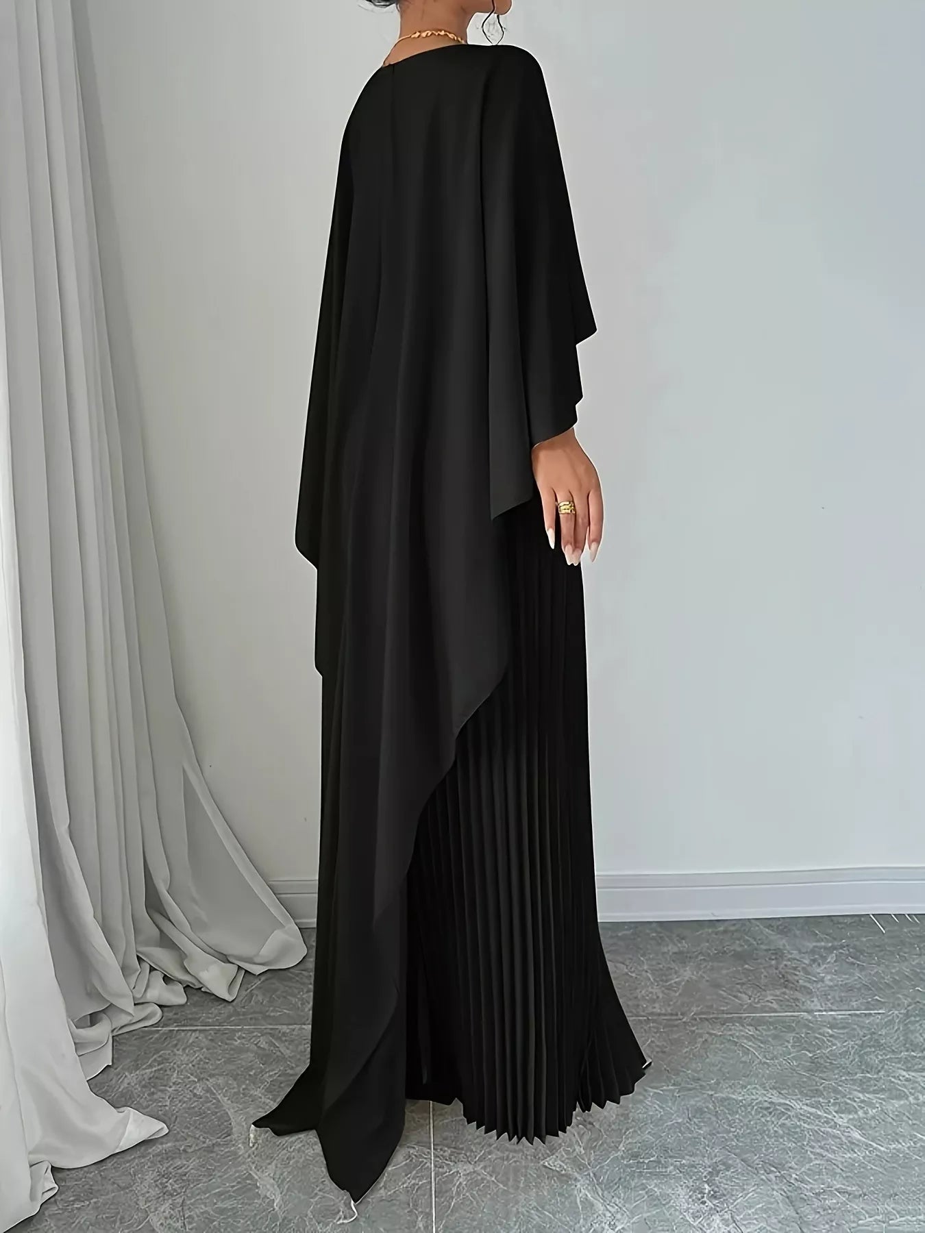 Woman wearing a Cape Pleated Maxi Dress with flowy pleats and no stretch, made of 100% polyester